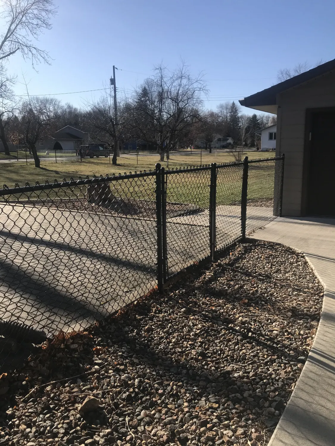 Tall black chain link fence with sturdy posts beside a modern Minneapolis home