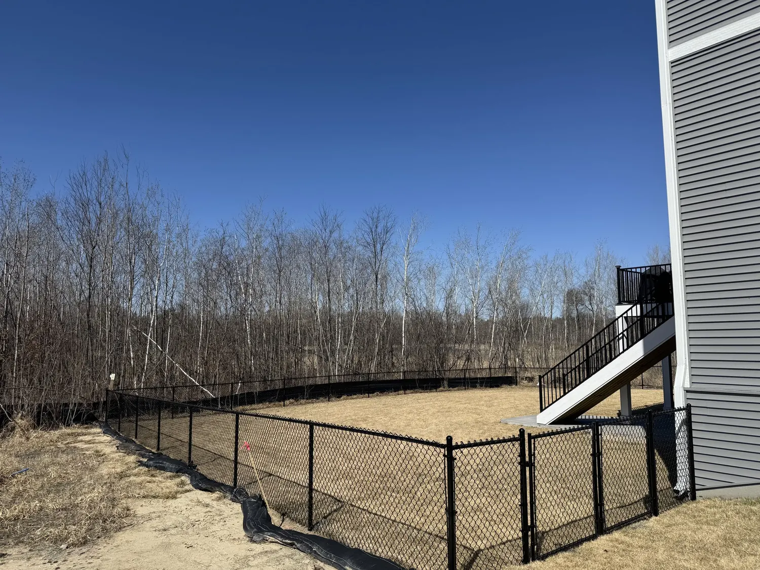 Replacement black metal fence beside an open field under a blue sky in the Twin Cities